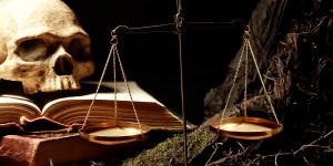 Human skull on old books near weight scales